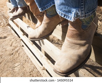 Cowboys And Cowgirls Sitting On Wooden Fence.