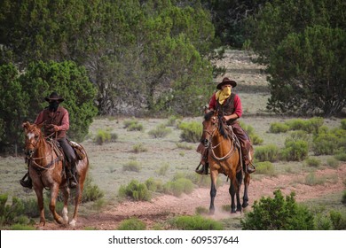 Cowboys Riding Horses In Desert With A Guns In Their Hands. Concept  Train Robbery.