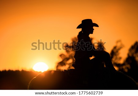 Cowgirl with her horse at sunset