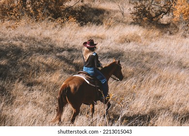 Cowgirl Horseback Ride Down Hill On Horse Through Texas Autumn Field During Fall Season.