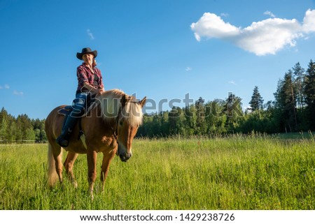 Cowgirl horseback riding at sunset