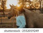 Cowgirl and palomino horse staring into sunset