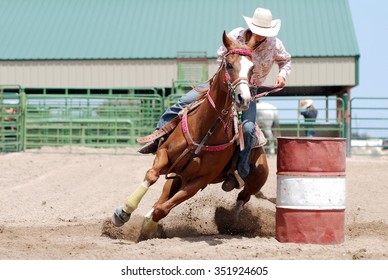 Cowgirl racing her horse between poles during a rodeo.