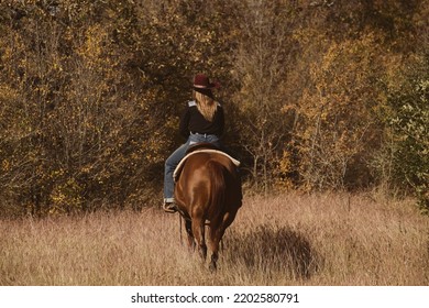 Cowgirl Riding Horseback Through Texas Field During Fall Season In Nature.