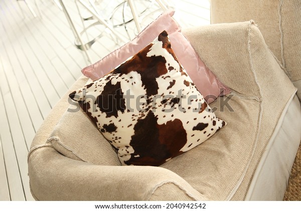 The cowhide\
pattern pillow on the empty armchair\
