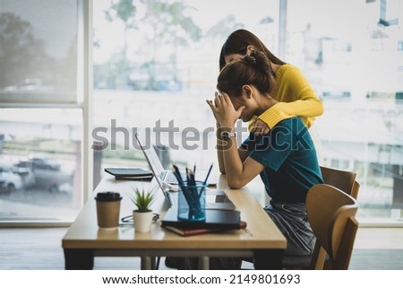 Coworker comforting stressed and discouraged woman in office.