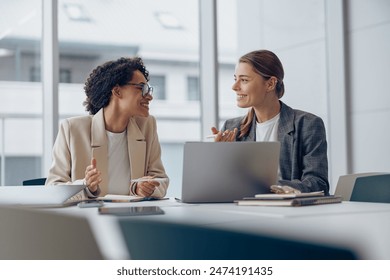 Coworkers discussing biz related problem in the office and using laptop. Conception of business team - Powered by Shutterstock