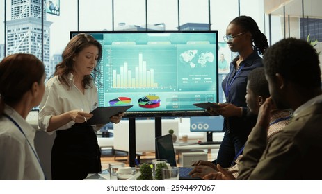 Coworkers engaging in a problem solving meeting at a corporation, using an interactive board to visualize data and develop solutions for complex business challenges. Analysis presentation. Camera B.