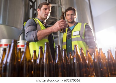 Coworkers examining beer bottles at factory - Powered by Shutterstock