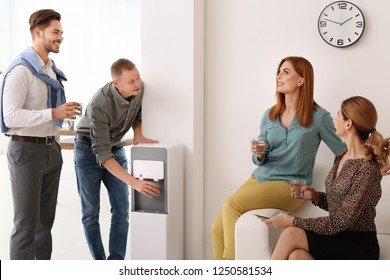 Co-workers having break near water cooler at workplace - Powered by Shutterstock