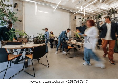 Coworkers moving around, collaborating, and using laptops in a dynamic office environment filled with plants