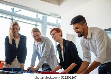 Coworkers Playing A Foosball Table In An Office.