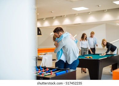 Coworkers Playing A Foosball Table In An Office.