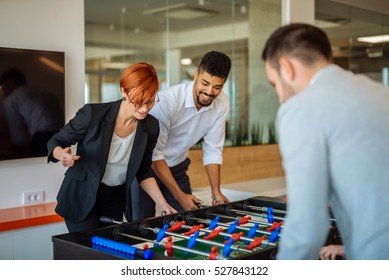 Coworkers playing a foosball table in an office. - Powered by Shutterstock