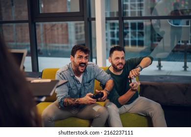 Coworkers playing video games in an office during a work break. Two male colleagues sitting in a coworking place in a friendly atmosphere. - Powered by Shutterstock