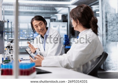 Coworkers talking, doing genetics study using clinical equipment in medical lab. Team of biotechnologists doing brainstorming, using scientific gear in research facility, doing complex experiments