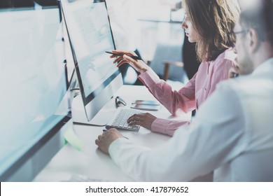 Coworkers team in modern office.Project managers work new idea.Young business crew working with startup studio.Desktop computer table,showing presentation,reflection monitor.Blurred,film effect. - Shutterstock ID 417879652