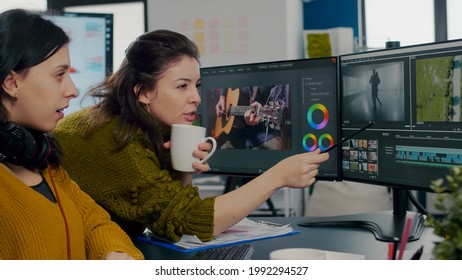 Coworkers video editors discussing in front of pc working for client footage using post production software and two monitors. Creative People processing film montage in digital multimedia company - Shutterstock ID 1992294527