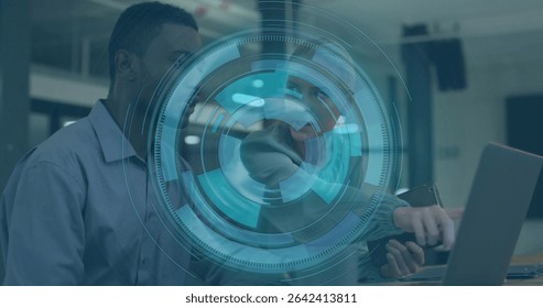 Coworkers wearing business casual attire working on laptop in office, with smartphone, data overlay. Collaboration, teamwork, digital interface, data analytics, corporate, professional, modern