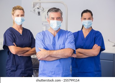 Co-workers wearing surgical mask with arms crossed in dental clinic
