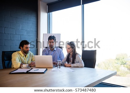 Coworkers working around a table with a laptop in the office