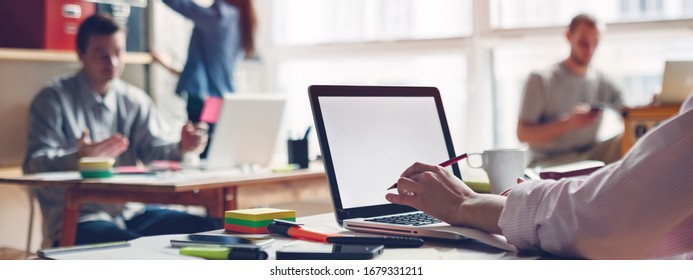 Coworking Station. Modern Business Loft And Millenials Working Together. Blank Laptop Typing. Intentional Sun Glare And Blurry Background. Wide Screen. Panoramic