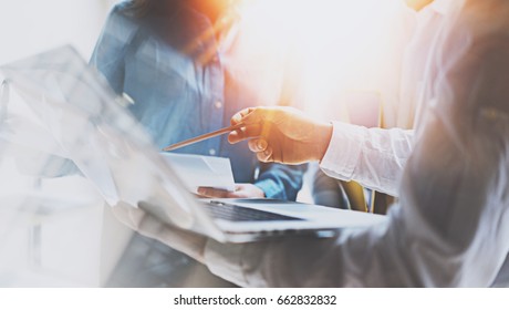 Coworking team meeting.Group of young businessmans working with new startup project at sunny office.Man pointing on laptop screen.Blurred background.Flares effects