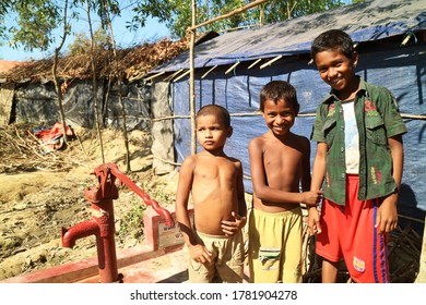 COX'S BAZAR, BANGLADESH - NOVEMBER 9, 2017: Rohingya Refugee Boys Pose With Traditional Water Pump.