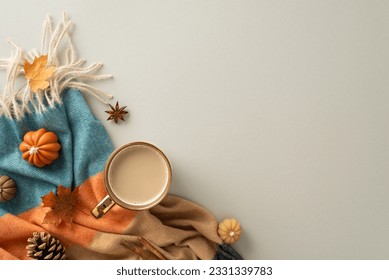 Coziness of being at home in autumn. Above view photo of a cup of hot coffee, patchy blanket, pumpkin-shaped candles, maple foliage and aromatic spices on grey isolated background with copy-space
