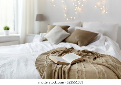 Coziness, Comfort, Interior And Holidays Concept - Cozy Bedroom With Bed And Christmas Garland Lights At Home