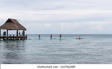 COZUMEL, MEXICO - NOVEMBER 18, 2017: Vacationers Paddleboarding And Kayaking On Calm Ocean Waters.