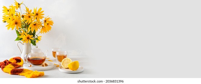 Cozy autumn banner. Hot teapot, two cups of tea, yellow flowers bouquet, lemon and knitted scarf on white background side view. Autumn, fall, tea party concept. Restaurant Web line, sale. Copy space  - Powered by Shutterstock