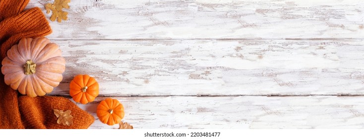 Cozy Autumn Corner Border With Pumpkins, Leaves And Sweater. Overhead View On A Rustic White Wood Banner Background.