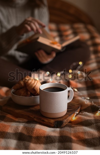 cozy\
autumn evening: girl, coffee, book and\
croissants