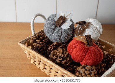 A cozy autumn scene featuring a woven basket filled with pine cones and knitted pumpkins, showcasing the warmth and charm of the season. Perfect for fall-themed designs. - Powered by Shutterstock