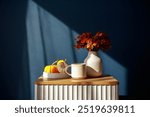 Cozy autumn still life with a warm cup, vibrant fall foliage in a vase, and decorative pumpkins on a ribbed bedside table. Perfect for seasonal decor and cozy vibes