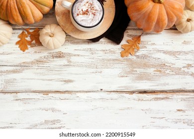 Cozy Autumn Top Border With Pumpkins, Leaves, Sweater And Pumpkin Spice Latte. Overhead View Over A Rustic White Wood Background.