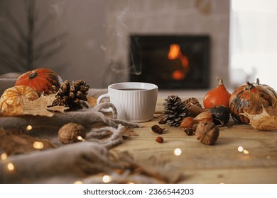 Cozy autumn. Warm cup of tea, pumpkins, autumn leaves, cones, cozy scarf and lights on rustic wooden table in farmhouse. Fall in rural home. Happy Thanksgiving. Fall hygge still life, banner - Shutterstock ID 2366544203