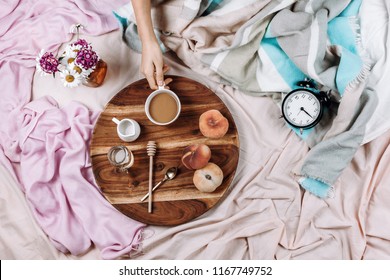 Cozy Autumn Or Winter Flatlay Of Wooden Tray With Cup Of Coffee, Peaches, Creamer With Plant Milk, Syrup And Spoons On Pastel Sheets And Woman's Hand, Selective Focus