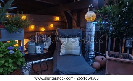 A cozy balcony corner with warm string lights, lush plants, a comfy lounge chair, and decorative lanterns creates a relaxing and inviting evening atmosphere perfect for unwinding.
