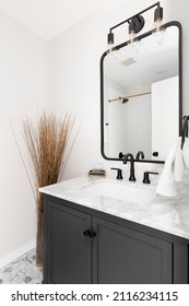 A Cozy Bathroom With A Grey Vanity Cabinet, Hexagon Marble Tiled Floor, And White Granite Countertop.