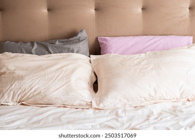 Cozy bed with colorful pillows and beige headboard. Neat and inviting bedroom set. - Powered by Shutterstock