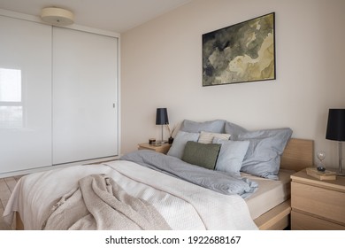 Cozy bedroom with big and comfortable bed with nice bedclothes and wardrobe with white sliding doors