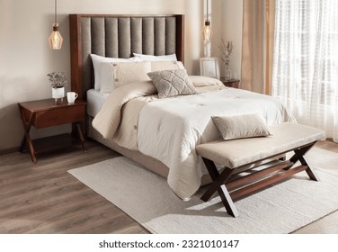 A cozy bedroom featuring a queen-sized bed placed next to a wooden table and a window - Powered by Shutterstock