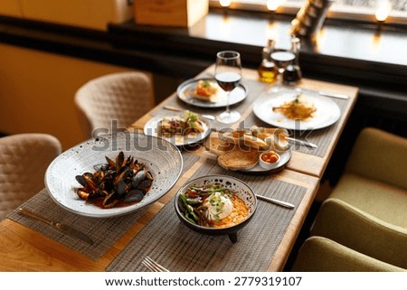 Cozy Bistro Table Set With Shared Dishes And Bread, Rustic Ceramics And Warm Light Create Communal Meal Atmosphere, Mussels, Soups And Side Bowls