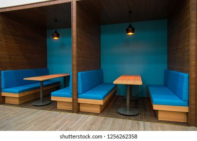 Cozy blue sofas near table in popular cafe. Modern interior of public establishment with compartment walls. Coworking space concept