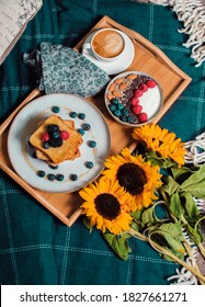 Cozy Breakfast In Bed. Yogurt Bowl With Raspberries, Blueberry, Chocolate And Nuts, French Toasts, Coffee Cup On Wooden Plate. Sunflowers. Close Up Still Life From Above. Food Photography. 