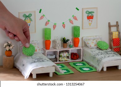 A Cozy Bright Dollhouse Bedroom, A Woman Hand Decorating The Bed With A Knitted Pillow