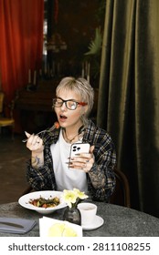 In a cozy cafe, a stylish non binary person enjoys a scrumptious meal while lost in thought.