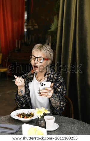 In a cozy cafe, a stylish non binary person enjoys a scrumptious meal while lost in thought.